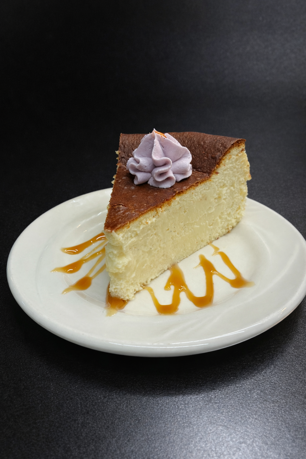 A slice of Basque cheesecake with ube Chantilly and caramel